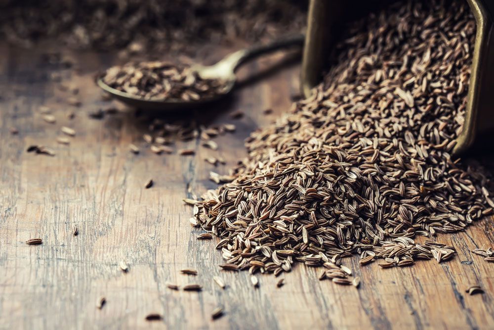 A spoon of Cumin and Cumin on the table