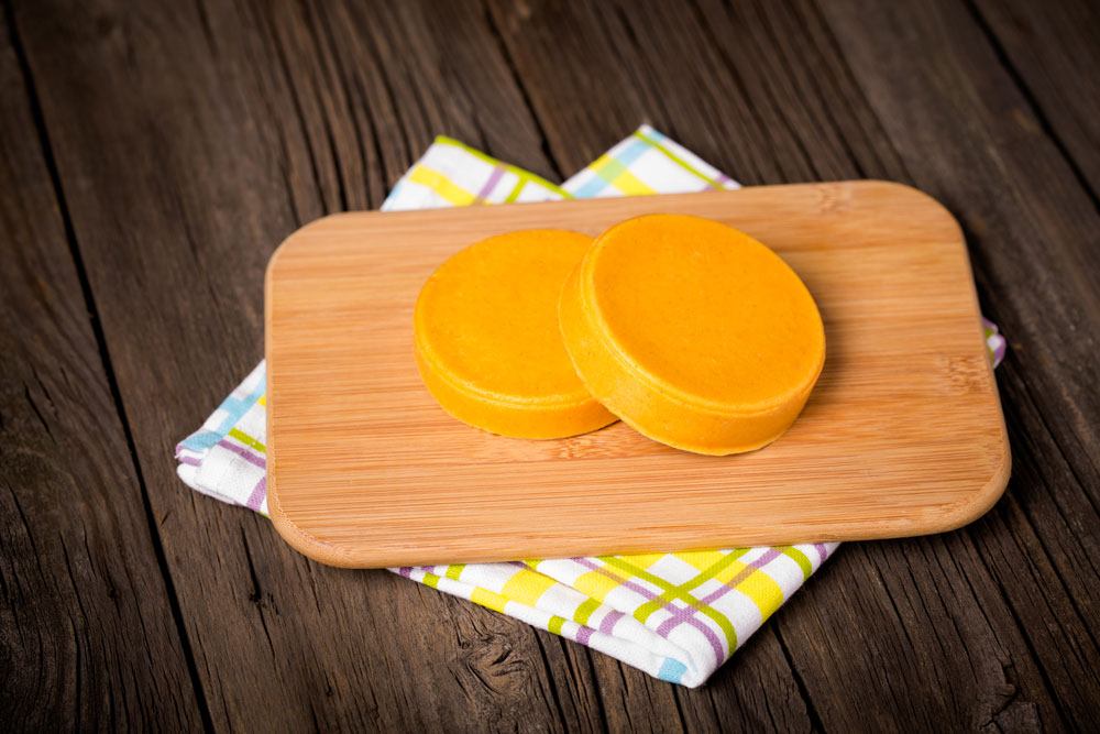 Two pieces of Asiago cheese on the chopping board