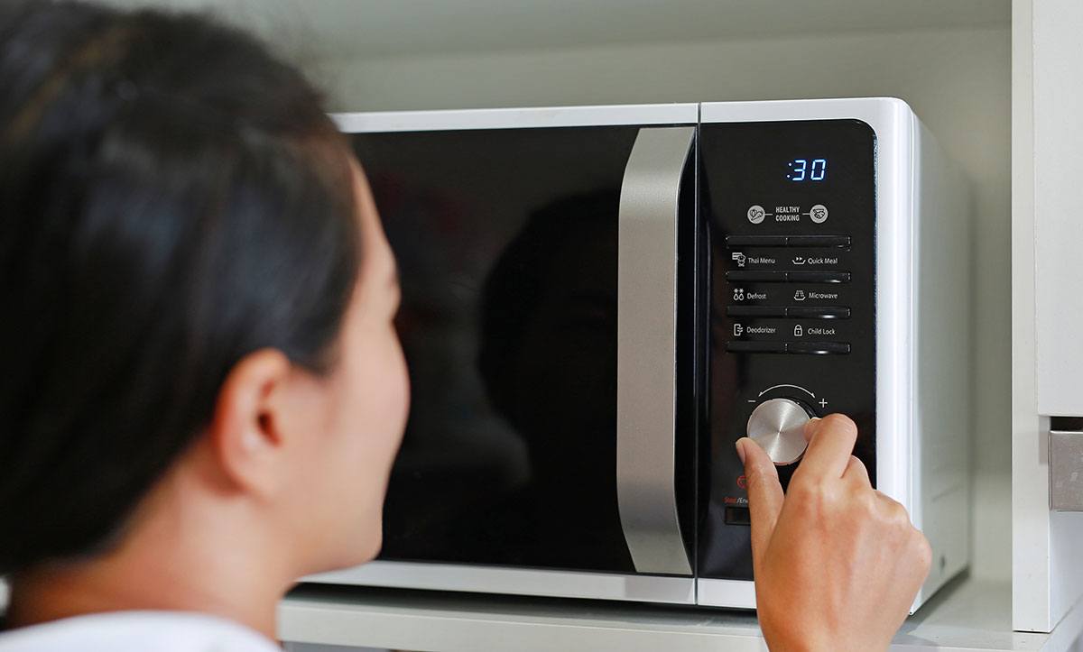 A woman is using the microwave