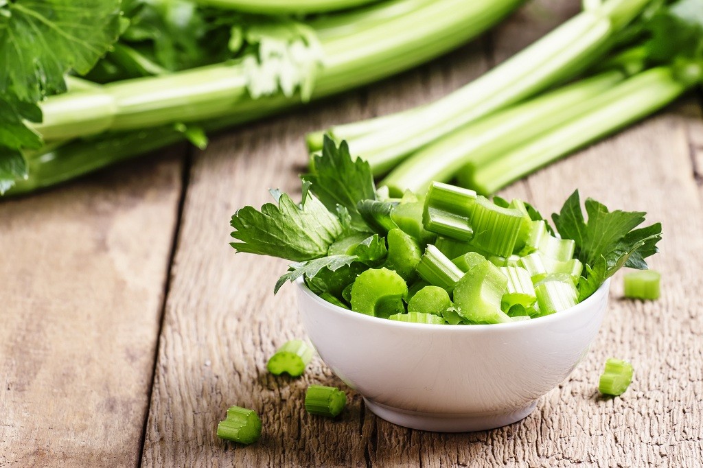 A bowl of sliced celery and celeries on the table