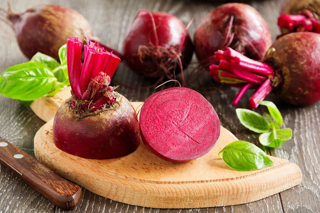 Beets on the chopping board and a knife on the table