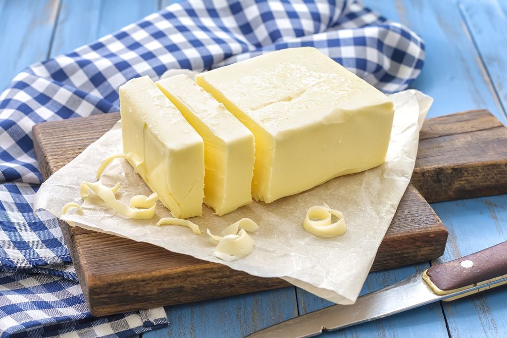 butter and slices of butter on the chopping board and a knife