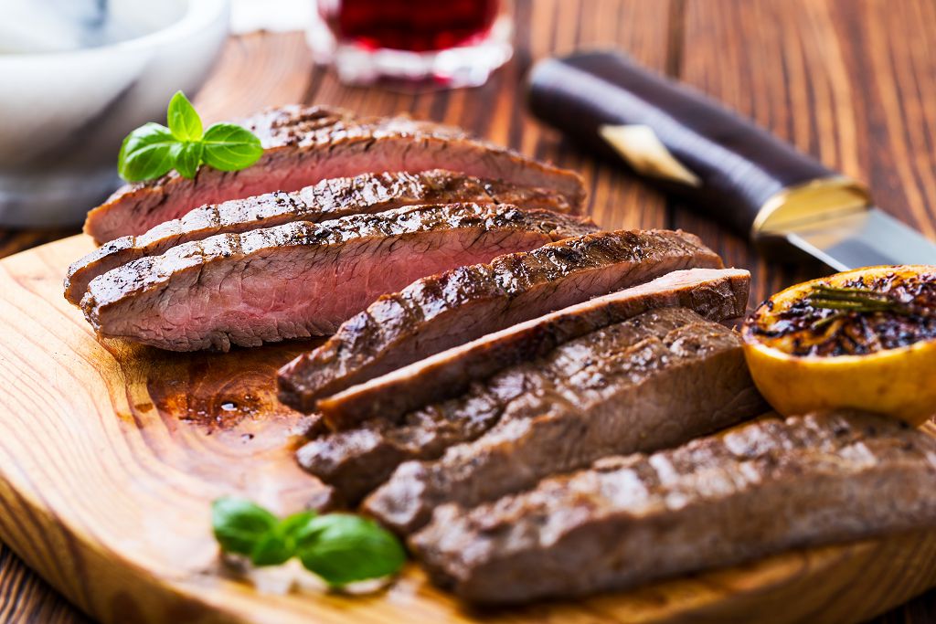 Slices of beef steak on the chopping board and a knife