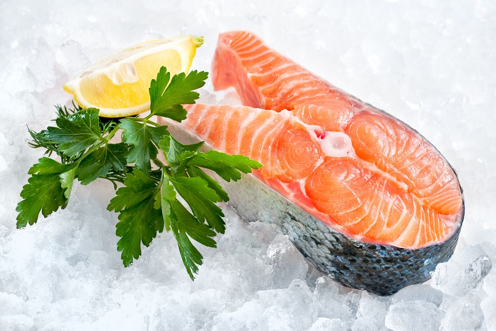 pieces of fresh salmon and sliced lemon on the ice