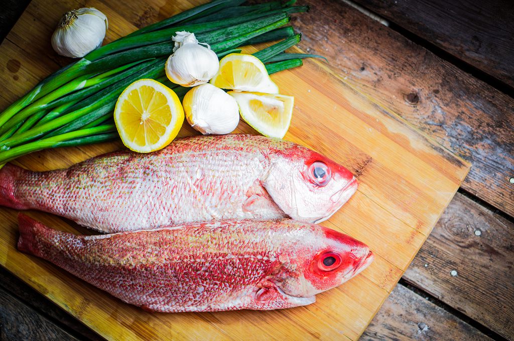 Fresh Snapper, slices of lemon and scallions on the chopping board