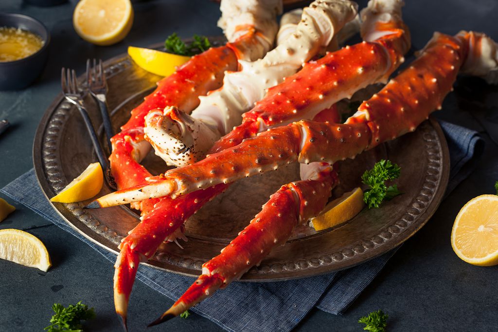 A plate of crab legs, forks and slices of lemon