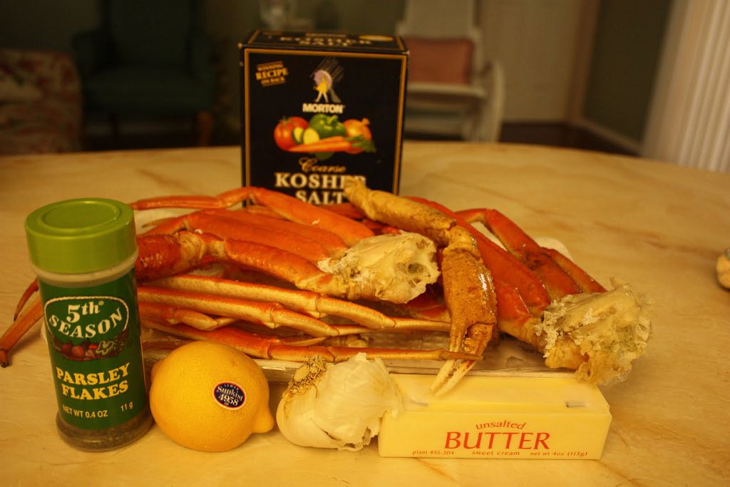 A plate of crab legs, lemon, garlic head and Butter