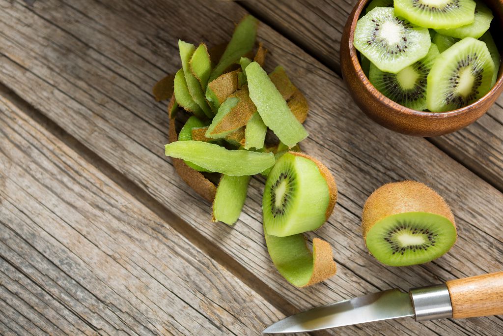 a bowl of sliced kiwi, slices of kiwi and a knife