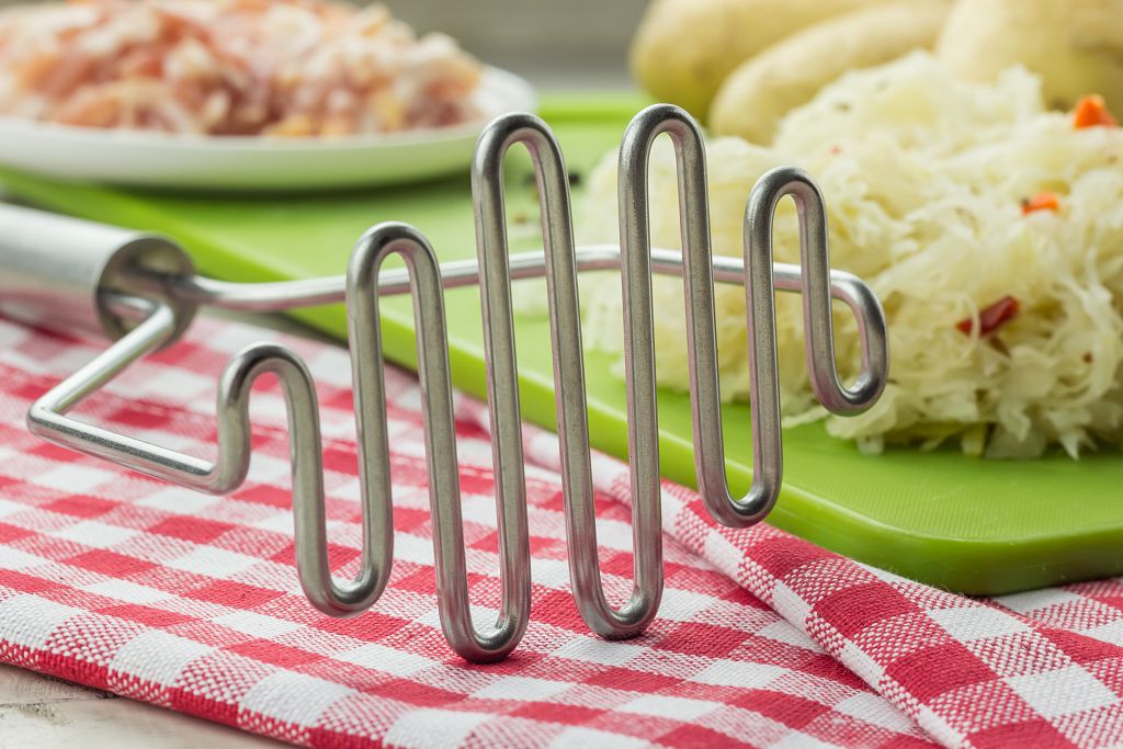 A Potato Masher and vegetables on the table