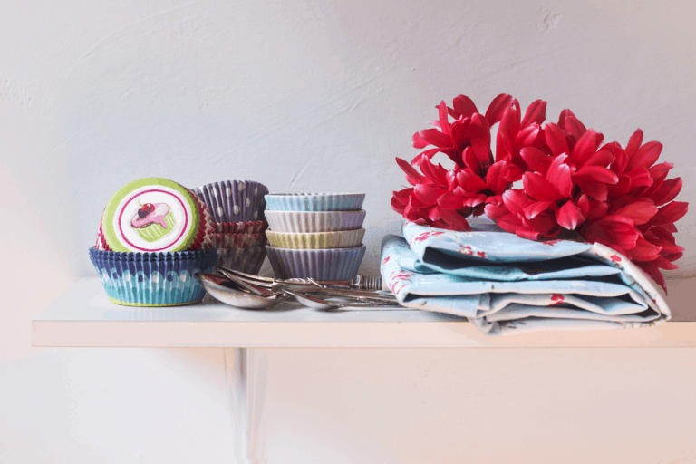 Colorful cupcake wrappers over a shelf in a rustic kitchen