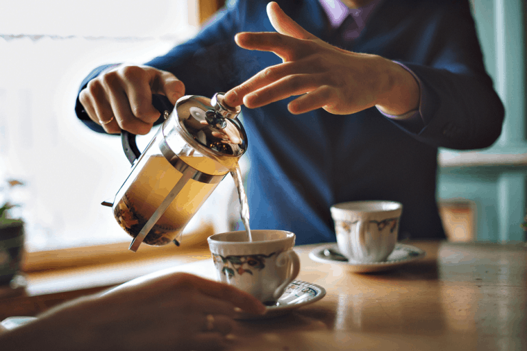 Man pouring herbal tea in a mug of French press.