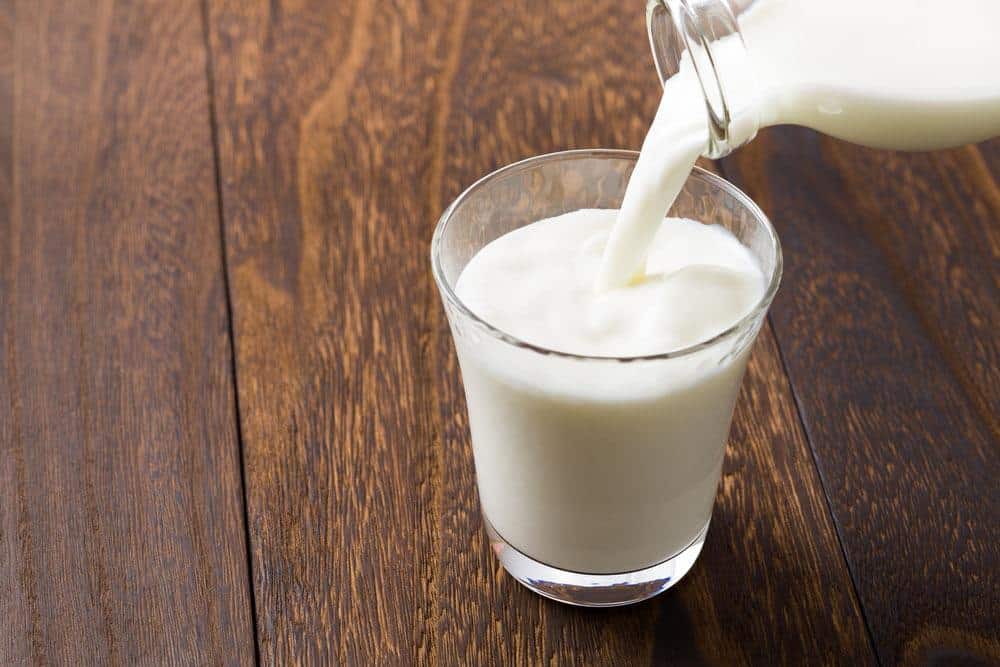 A bottle of Condensed Milk and a cup of Condensed Milk