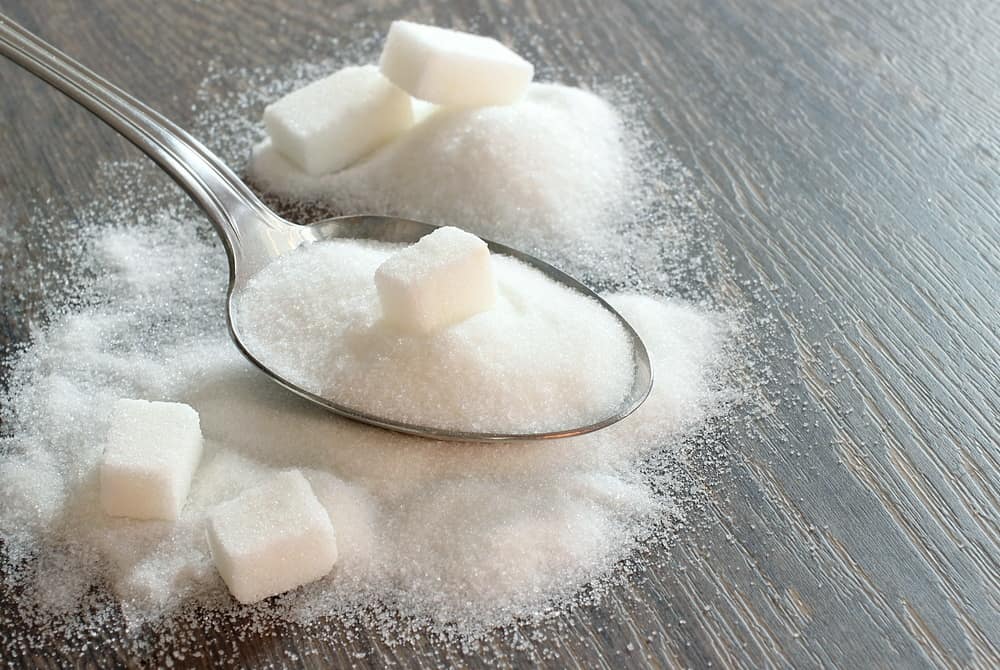 A spoon of Refined Sugar and Refined Sugar on the table