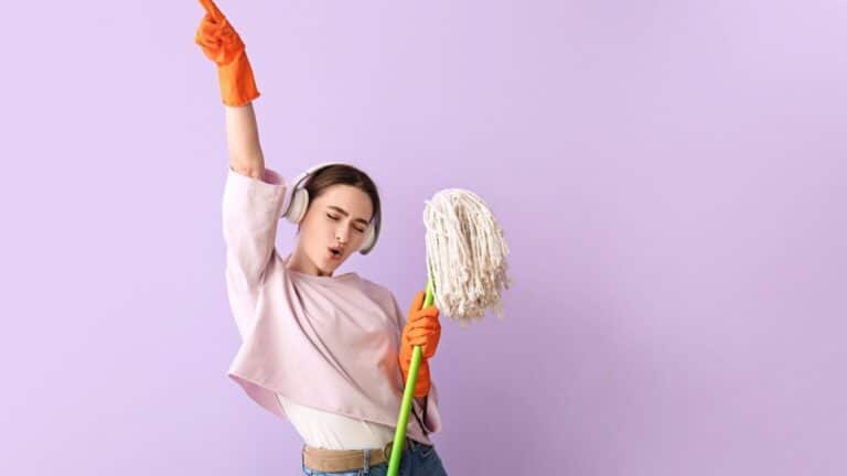 Young woman with floor mop listening to music